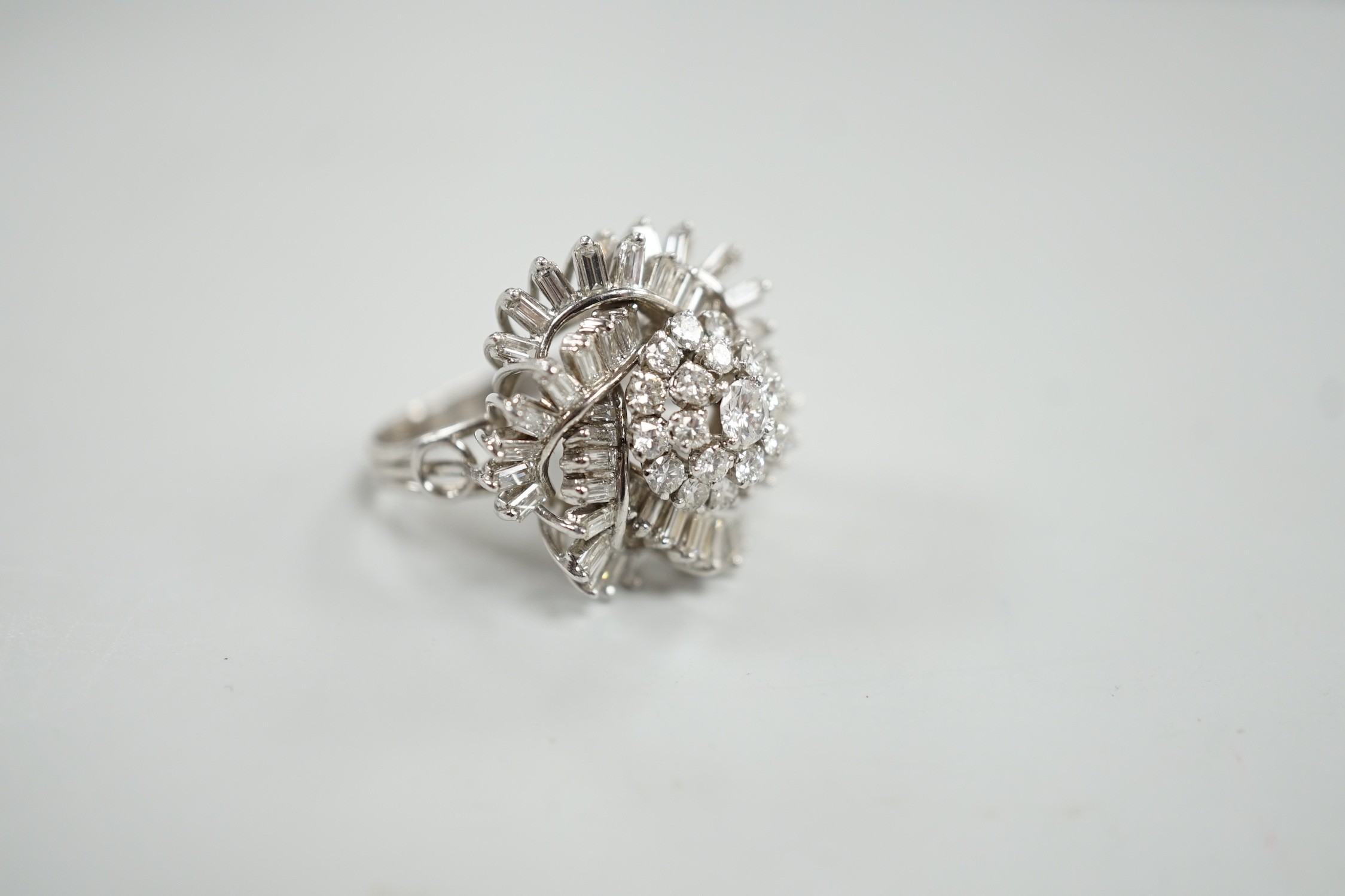 A white metal, baguette and round cut diamond spiral cluster set dress ring, size P, gross weight 14.7 grams.